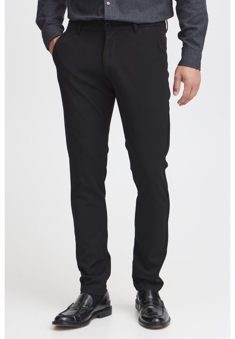 Czarne dopasowane spodnie wykonane z gładkiego materiału, z tradycyjnym zapięciem na guzik, bocznymi kieszeniami i dopasowanym krojem.