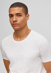 T-shirt blanc en coton doux. Doté d'un col ras du cou et d'un petit logo "BOSS" brodé sur la poitrine gauche. Manches courtes.