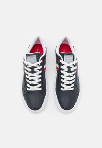 Navy leather sneakers with white laces, featuring a red and white striped accent, and a padded collar. Brand logo on the tongue.