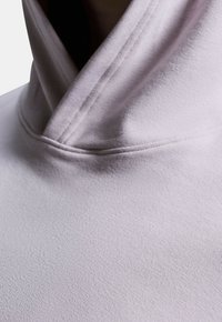 Světle fialová mikina s vysokým límcem vyrobená z měkké tkaniny, s hladkým povrchem a jemnými švy podél švů.