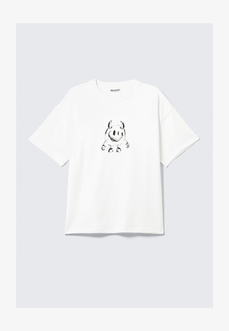 T-shirt blanc en coton à manches courtes avec un dessin de personnage de dessin animé noir avec des cornes et les bras positionnés au centre.