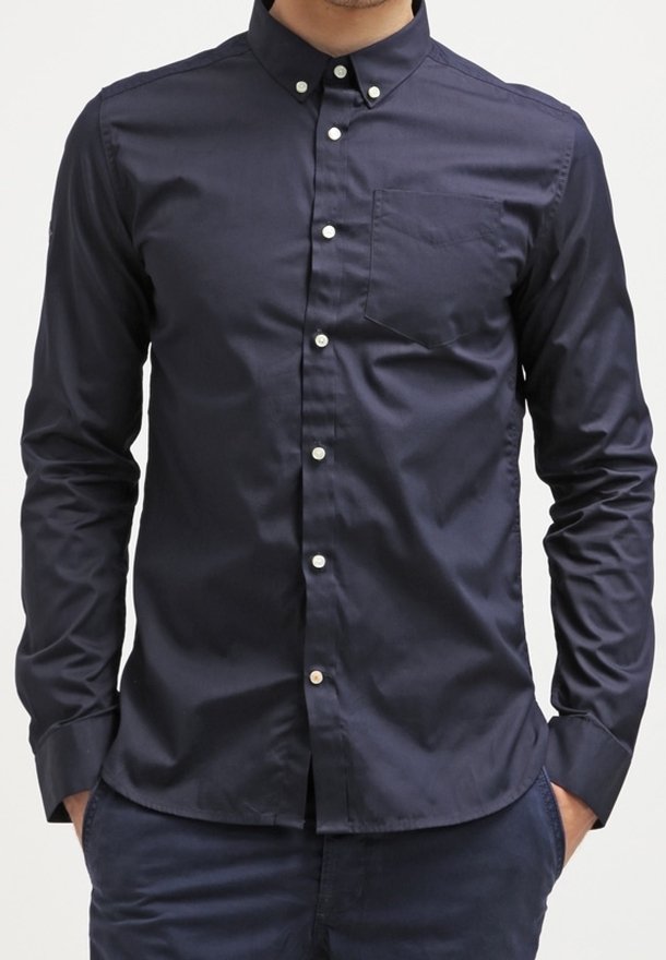 Námornícky modrá košile s dlouhým rukávem na knoflíky, vyrobená z hladké bavlny, s kapsou na hrudi a bílými knoflíky podél přední légy.