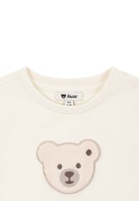 Sudadera de algodón en color crema con un diseño texturizado de cara de oso en el pecho. Presenta un escote redondo y una tela ligera.