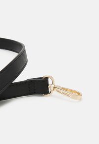 Svart läderrem med en slät yta, med en gyllene metallklipp och accentdetaljer, märkt "Valentino."