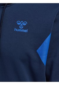 Sweat-shirt bleu marine avec un logo et un accent bleus. Fabriqué en tissu doux, avec une texture lisse et un design à panneau diagonal bleu.