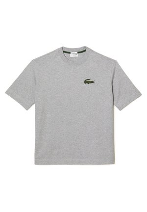 Graues Baumwoll-T-Shirt mit Rundhalsausschnitt und kurzen Ärmeln; verfügt über ein grünes Lacoste-Krokodil-Emblem auf der linken Brust.