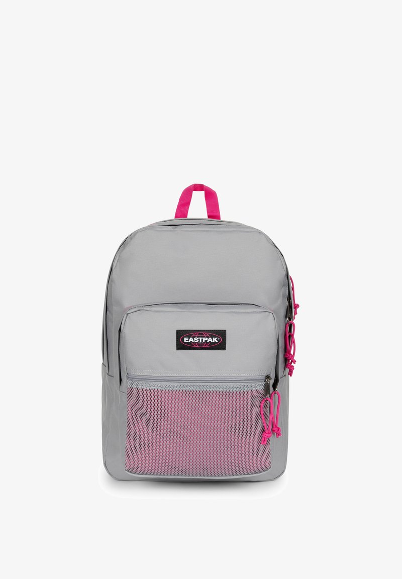 Sac à dos Eastpak gris clair avec fermetures éclair roses, poignée rose, poche avant en mesh et écusson logo sur la poche avant.