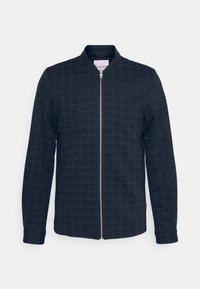 Giacca blu scuro con sottile motivo a griglia, maniche lunghe e zip argentata frontale su sfondo chiaro.