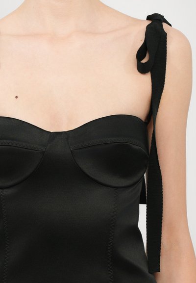 Top de satén negro con escote corazón, copas estructuradas y lazos de cinta en los hombros. Textura suave y diseño ajustado.
