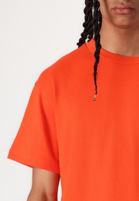 Korte mouw oranje T-shirt van katoen, met een ronde hals en een klassieke pasvorm. Zachte textuur met subtiele stikdetails.
