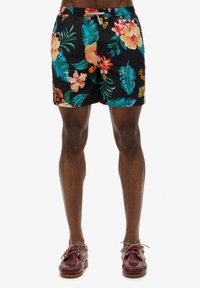 Shorts de baño negros con estampados tropicales brillantes, cinturilla elástica con cordón y un pequeño logo en la pierna.