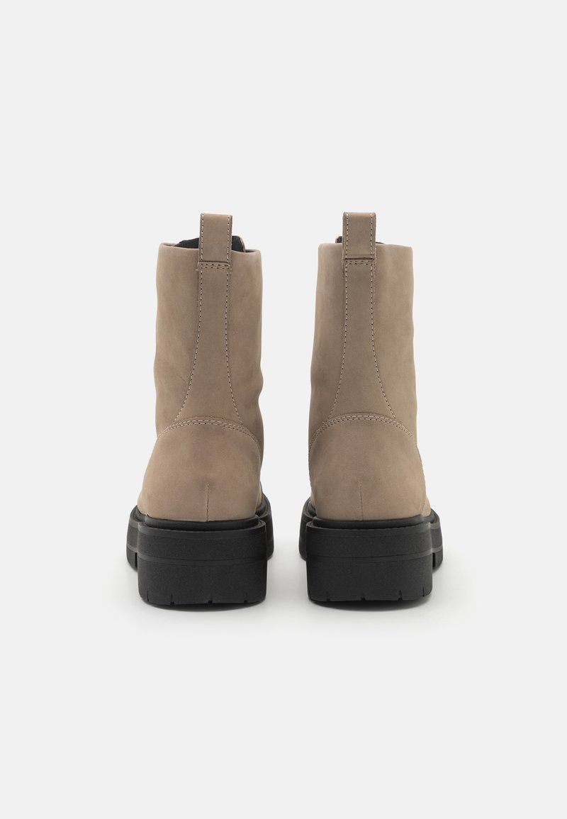 Beige Wildleder-Ankle Boots mit einer glatten Oberfläche, schwarzer Gummisohle und einem hinteren Ziehschlauf für einen einfachen Einstieg. Mit genähten Details an den Seiten.