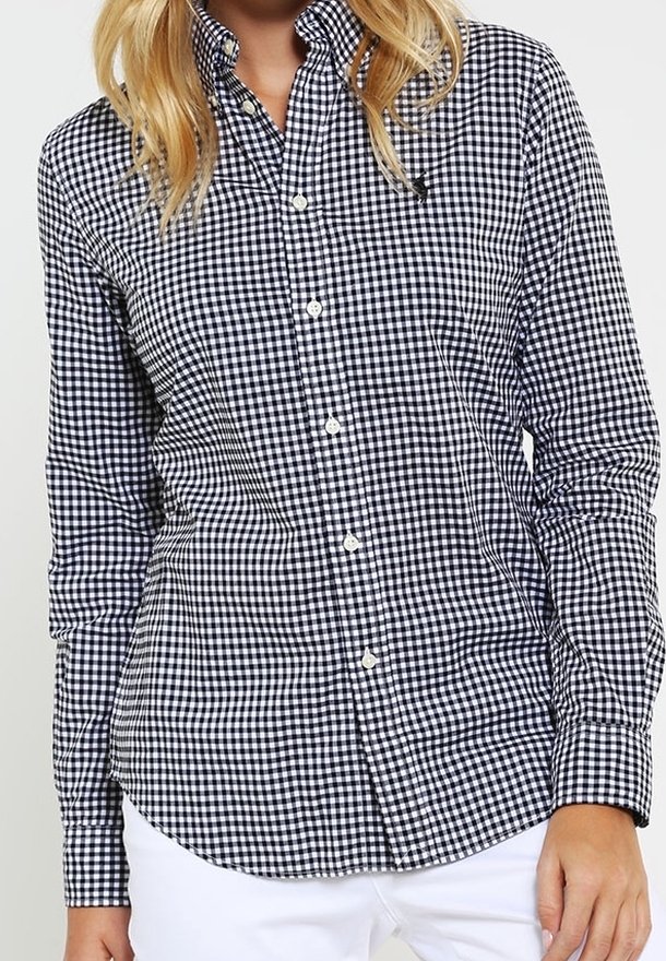 Black and white gingham button-up shirt with long sleeves, collar, and a straight hem. Features small round buttons and a classic fit.