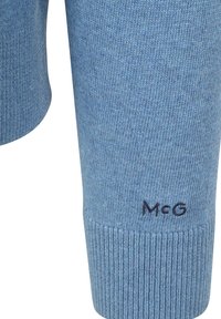 Hellblauer, gestrickter Pullover mit gerippten Bündchen; verfügt über ein kleines, gesticktes "McG"-Logo nahe dem Saum. Weiche Textur und glatte Oberfläche.