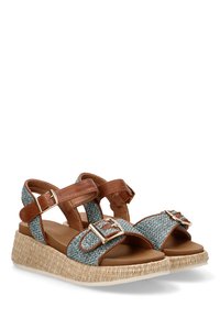 Sandalias de cuña de tela azul tejida con correas de cuero marrón y hebillas doradas. Presentan una suela natural envuelta en yute.