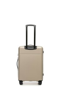 Hard-shell suitcase in gold, featuring vertical ribbed texture, retractable black handle, and four black wheels for mobility.