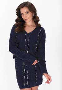 Rochie tricotată bleumarin, cu decolteu în V, textură ribbată și decorațiuni cu perlute aranjate în modele pe față.