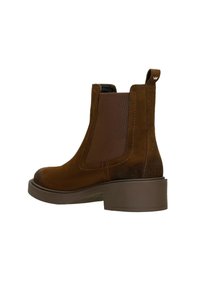 Brązowe zamszowe botki Chelsea z elastycznymi panelami bocznymi, okrągłym noskiem i niskim obcasem. Posiadają pętelkę z tyłu ułatwiającą zakładanie.