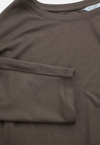 Braun langärmliges Hemd aus weichem Stoff, mit einem runden Ausschnitt und einem schlichten Design, das sichtbare Nähte an den Ärmel aufweist.