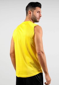 Maglietta atletica gialla senza maniche con una texture liscia e scollo rotondo, caratterizzata da un design aderente e cuciture rinforzate.