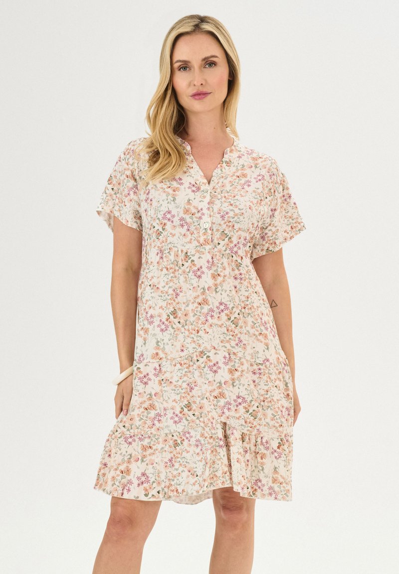 Robe florale en tissu doux, avec des manches courtes, un col boutonné et un ourlet froncé dans une palette de couleurs pastel de rose et de vert.