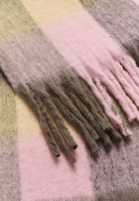 Uldhalsedisse med en blød tekstur og frynser, i nuancer af pink, brunt, gråt og lys gul, der viser et ternet mønster.
