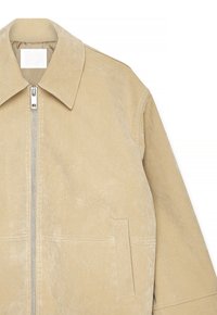 Beige suède jack met zilveren voorrits, brede kraag en verticale splitzakken op de torso, getoond tegen een witte achtergrond.