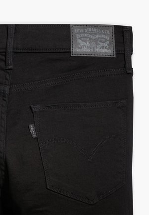 Svarta denimjeans med en strukturerad yta. Har en bakficka med ett signaturstickningsmönster och en grå läder-logotyp.