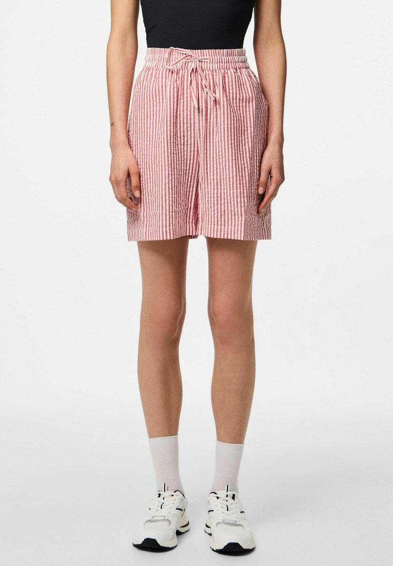 Červené a bílé pruhované šortky s elastickým pasem, stahovací šňůrkou a uvolněným střihem. Materiál vypadá jako lehký a prodyšný.