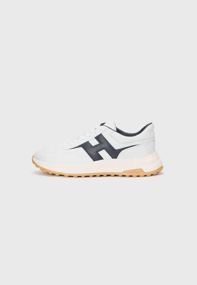 Baskets blanches avec un logo H noir, dotées d'une tige en cuir lisse, d'un col rembourré et d'une semelle en caoutchouc beige avec une texture antidérapante.