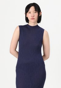 Rochie fără mâneci de culoare bleu marin, confecționată dintr-un material texturat, cu gât înalt, siluetă ajustată și un design minimalist. Fără modele sau accente vizibile.
