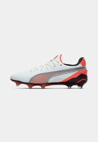 White soccer cleat with red and gray accents, featuring a textured upper, lace closure, and a sturdy black outsole with visible studs.