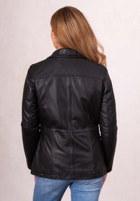Black leather jacket with structured shoulders, fitted design, and visible seam details. Back view shows a smooth texture and soft finish.