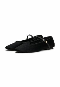 Un par de zapatos planos estilo Mary Jane negros con puntas afiladas, material texturizado y finas correas de hebilla sobre fondo blanco.