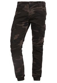 Męskie ciemne spodnie cargo w kamuflażu z guzikowymi klapkami na udach i elastycznymi mankietami przy kostkach, izolowane na białym tle.