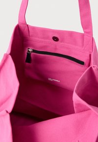 Ροζ τσάντα ώμου από καμβά με εσωτερική τσέπη με φερμουάρ σε μαύρο χρώμα και κλείσιμο με κουμπί. Φέρει το λογότυπο της μάρκας στο εσωτερικό. Μαλακή, ανθεκτική υφή.