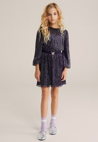 Violeta plīsēta kleita ar garām piedurknēm, sudraba mirdzums, josta ar metālisku akcentu. Apvienota ar sudraba baleta kurpēm un gaiši violetām zeķēm.