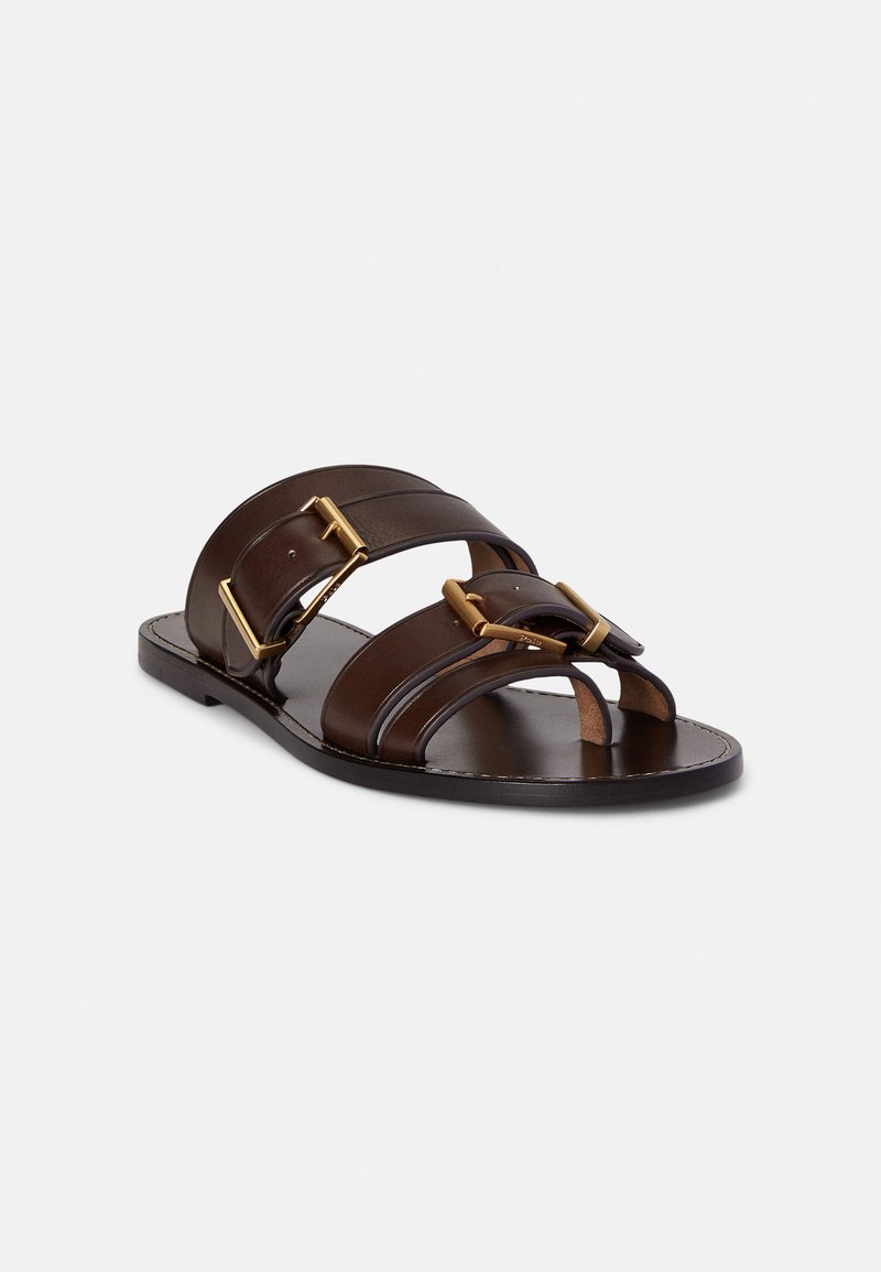 Brown leather slide sandals featuring two wide straps with gold-tone buckles, flat sole, and open-toe design.