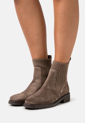 Bruna mockaankelstövlar med ribbad stickad tyg runt toppen, med platt sula och enkel, sömlös design.