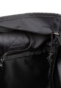 Musta kangaspussi, jossa on sileä vuori, vetoketjusuljenta ja kuminauhat. Varustettu ripustuslenkillä ja ommelluilla yksityiskohdilla.