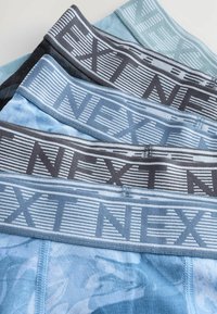Quattro paia di boxer in diverse tonalità di blu e grigio. Ognuno presenta un elastico con la scritta "NEXT" in un motivo a righe. Tessuto morbido e liscio.