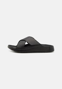 Infradito neri con design a fascia incrociata, realizzati in materiale morbido, con suola in EVA per il massimo comfort e dettagli traforati per la traspirabilità.