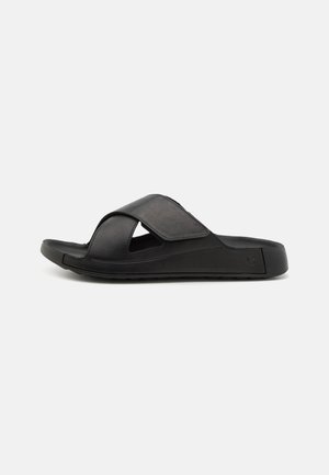 Sorte slidesandaler med kryssbånddesign, laget av mykt materiale, med EVA-yttersåle for komfort og utskjærte detaljer for god ventilasjon.