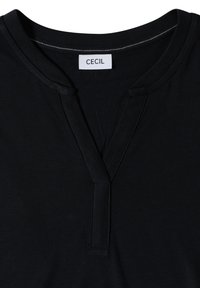 Chemise noire avec un col en V et une étiquette de marque "CECIL" blanche cousue à l'intérieur, au niveau de l'encolure arrière.