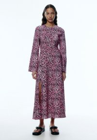 Rosa Leopardenmuster Langarmkleid mit einem Seitenschlitz, aus glattem Stoff; Model trägt schwarze Plateausandalen.
