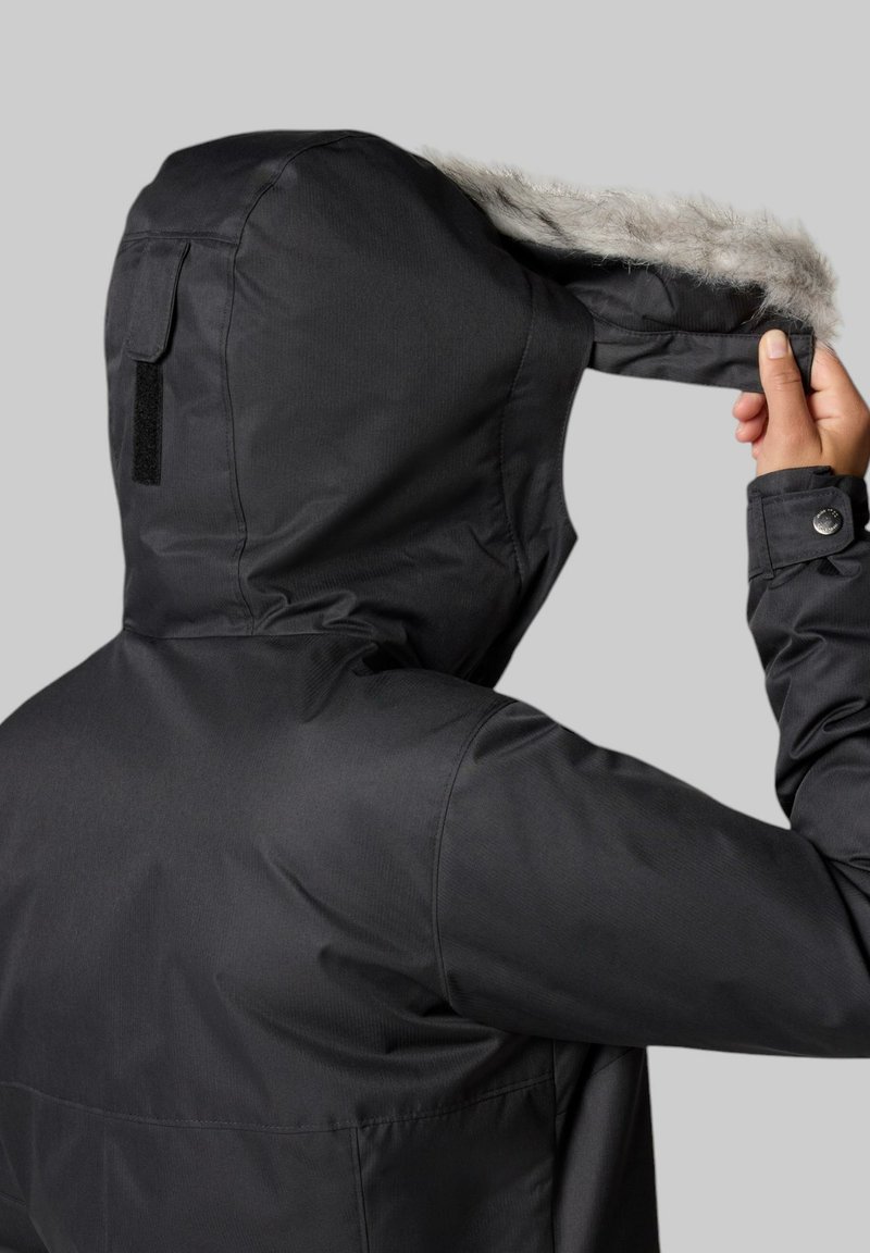 Schwarze Kapuzenjacke mit Kunstfellbesatz, mit strukturierter Oberfläche, verstellbarer Kapuze und geknöpften Manschetten. Die Rückansicht zeigt keine Taschen.