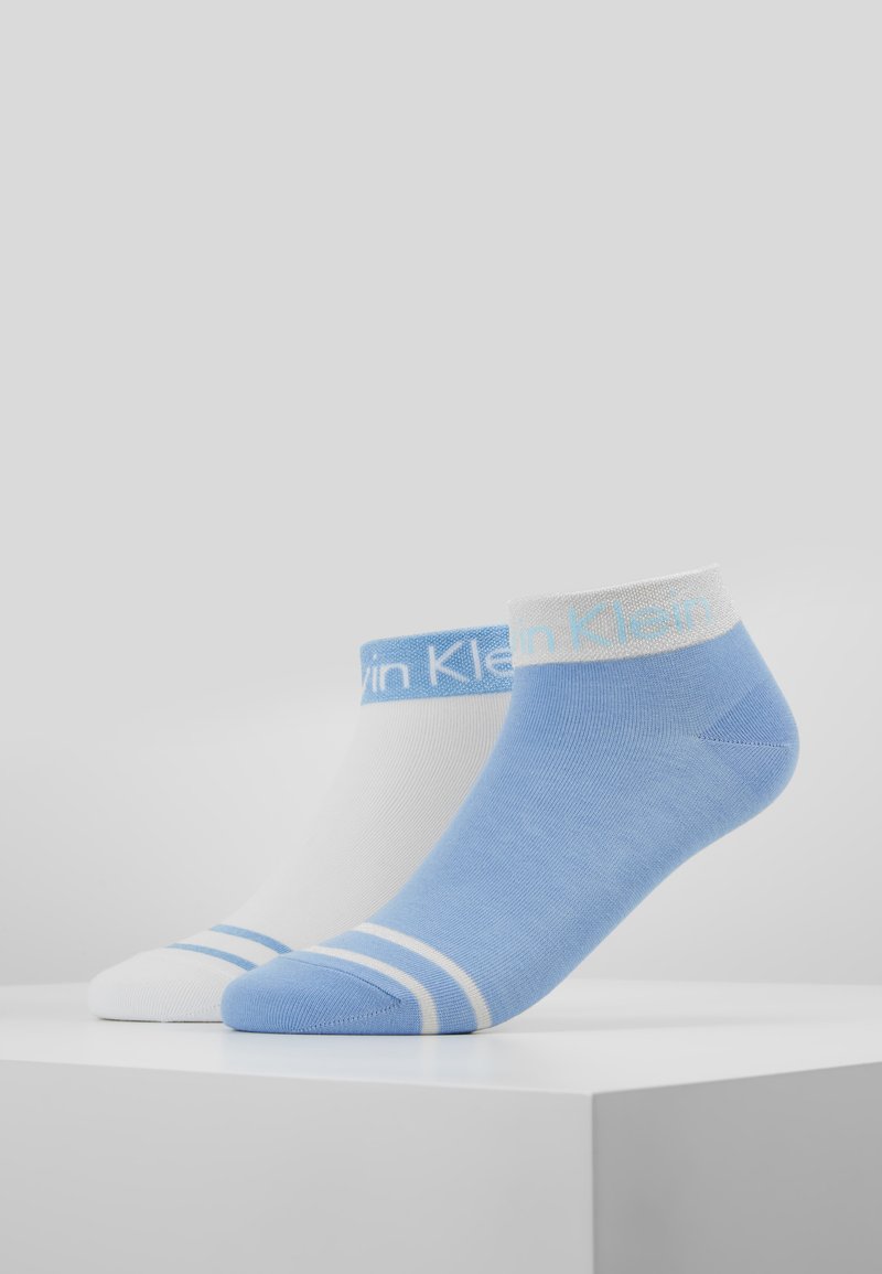 Zwei Paar Knöchelsocken: ein Paar weiß mit blauen Streifen, das andere hellblau mit einem weißen Band, beide mit dem "Calvin Klein"-Logo.