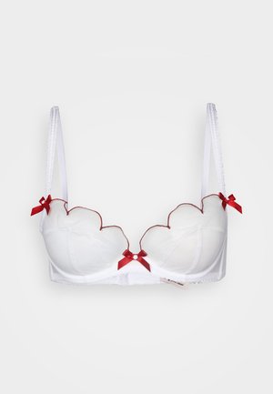 Sujetador blanco con diseño de borde en forma de ondas, tejido translúcido, acentos de cinta roja y tirantes ajustables. Presenta un pequeño adorno central como detalle.