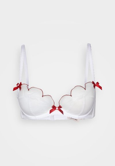 Fehér melltartó fodros mintával, áttetsző anyagból, vörös szalag díszítéssel és állítható pántokkal. Középen egy apró díszítőelem található.
