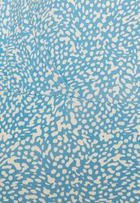 Tecido azul com um padrão de formas brancas espalhadas. O material tem uma textura suave com costuras visíveis ao longo das emendas.